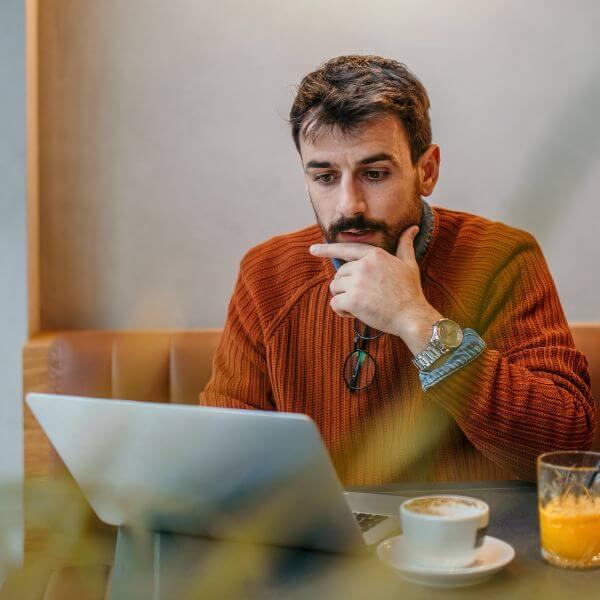 man-orange-reading-laptop man-orange-reading-laptop