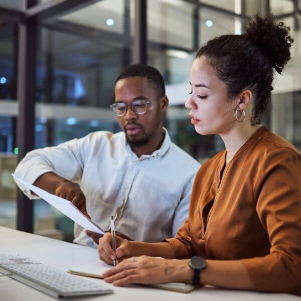 two people in office looking at a report two people in office looking at a report