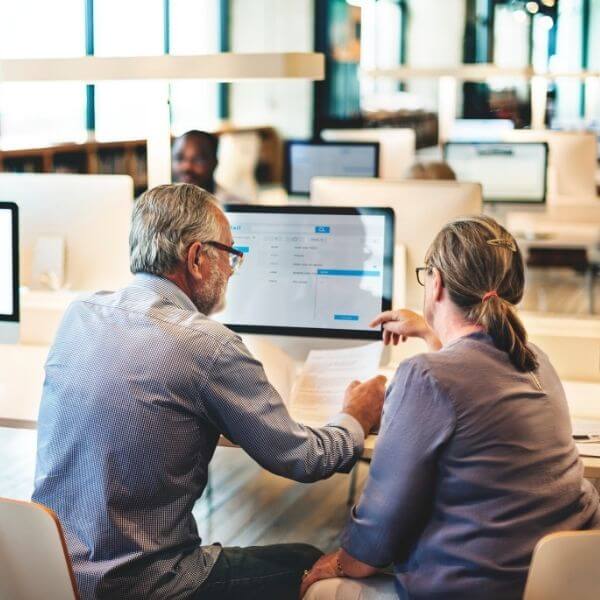 co-workers at a desk reviewing documents in front of their computers co-workers at a desk reviewing documents in front of their computers